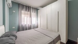 Makuuhuone, jossa on sänky, verhot, vaatekaappi ja ilmastointilaite.