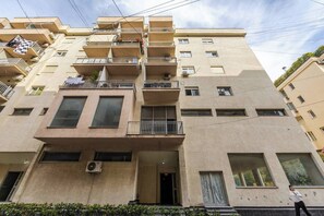 A multi-story residential building with balconies, air conditioning units, and a central entrance. - Sunset Apartment | 1BR Escape by PikHost (Durrës)