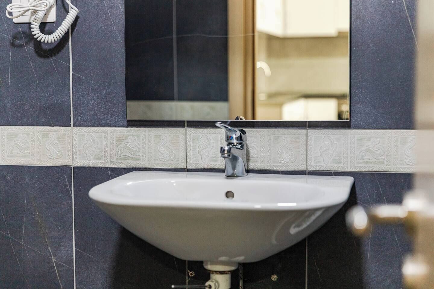 Un bany amb un lavabo blanc, un mirall a la part superior i un telèfon al mur.