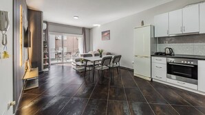 Moderni keittiö, jossa on ruokailutila, jääkaappi ja liesi.