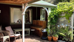 Une terrasse couverte avec un piano, des sièges et des plantes en pot.