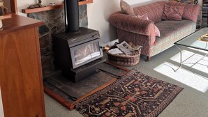 Un salon avec une cheminée en pierre, un canapé, une table basse et un tapis.