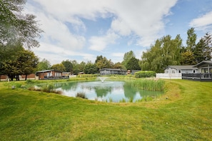 A pond with a fountain, surrounded by grass and trees, with buildings in the background. - Host Stay Rose Lodge (York)