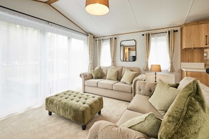 A living room with a sofa, ottoman, and a lamp. - Host Stay Rose Lodge (York)