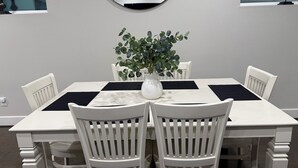 A dining table with white chairs, a white vase with a plant, and black placemats. - 3BR, 3.5Bath Home Near TMC, Downtown, Museums, NRG,Toyota CT, Discovery Green (Houston)