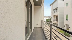 A narrow balcony with a metal railing, a glass door, and a view of adjacent buildings. - 3BR, 3.5Bath Home Near TMC, Downtown, Museums, NRG,Toyota CT, Discovery Green (Houston)
