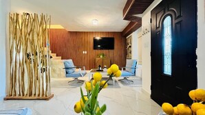 Un soggiorno moderno con televisore, posti a sedere e un'angolare decorativa con piante.