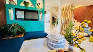 Un soggiorno moderno con un divano blu, un poggiapiedi rotondo, un camino e una pianta decorativa.