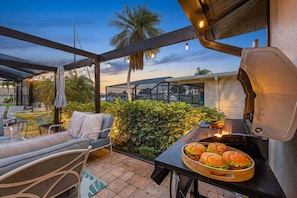 Eine Terrassengaststätte mit Grill, Sitzgelegenheiten und Blick auf eine Wohngegend.
