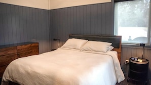 Una camera da letto con un letto, un comodino, una lampada e una finestra con vista.