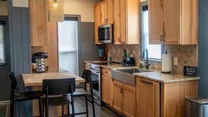 Una cucina compatta con mobili in legno, un forno a microonde, un piano cottura e un lavello.