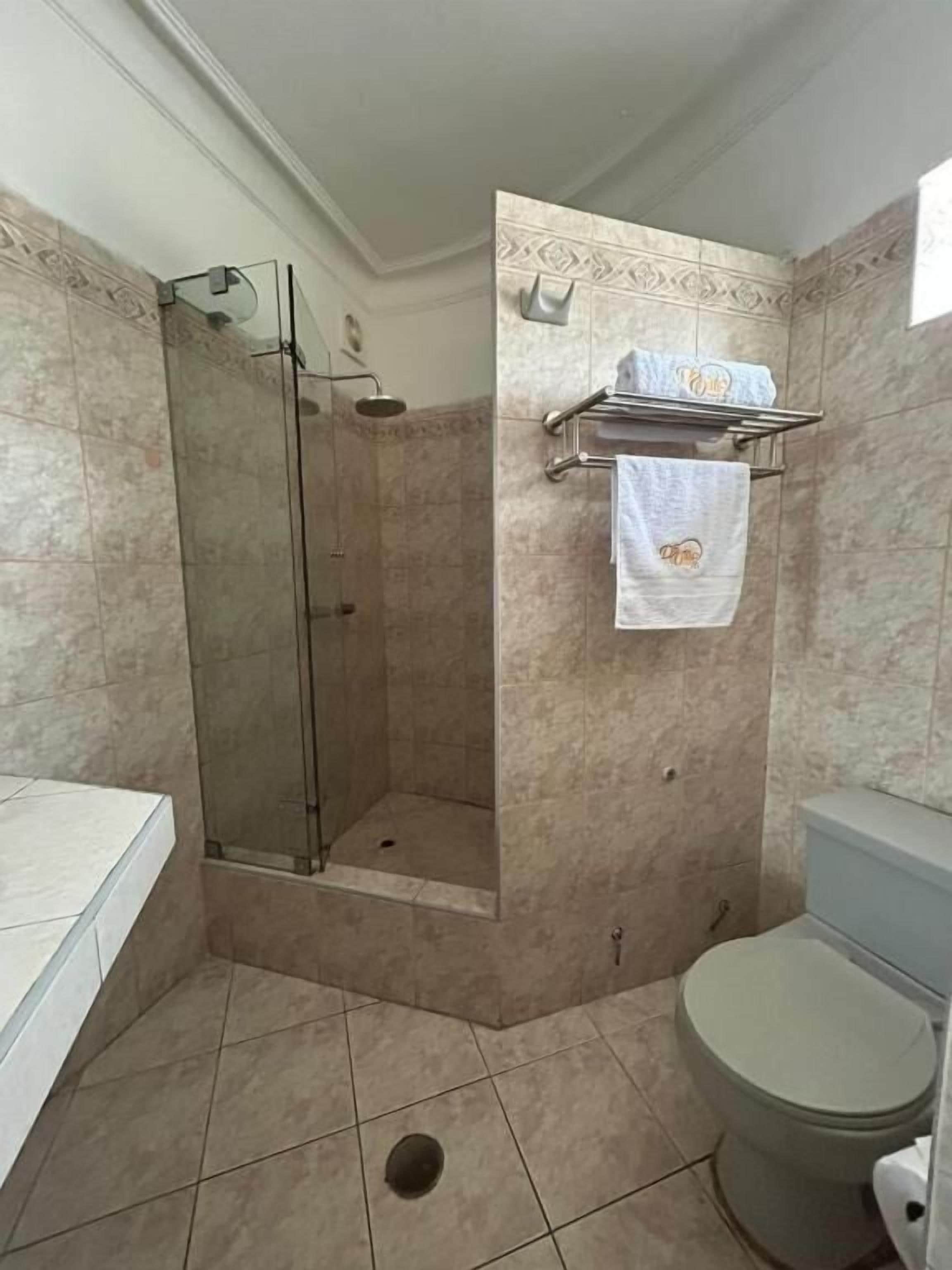 Un baño con cabina de ducha de vidrio, inodoro y lavabo.