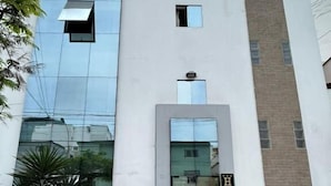 Un edificio moderno con fachada de vidrio, una entrada central y un letrero con la letra 'H'.