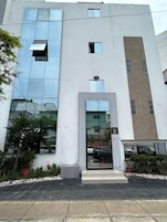 Un edificio moderno con fachada de vidrio, una entrada central y un letrero con la letra 'H'.