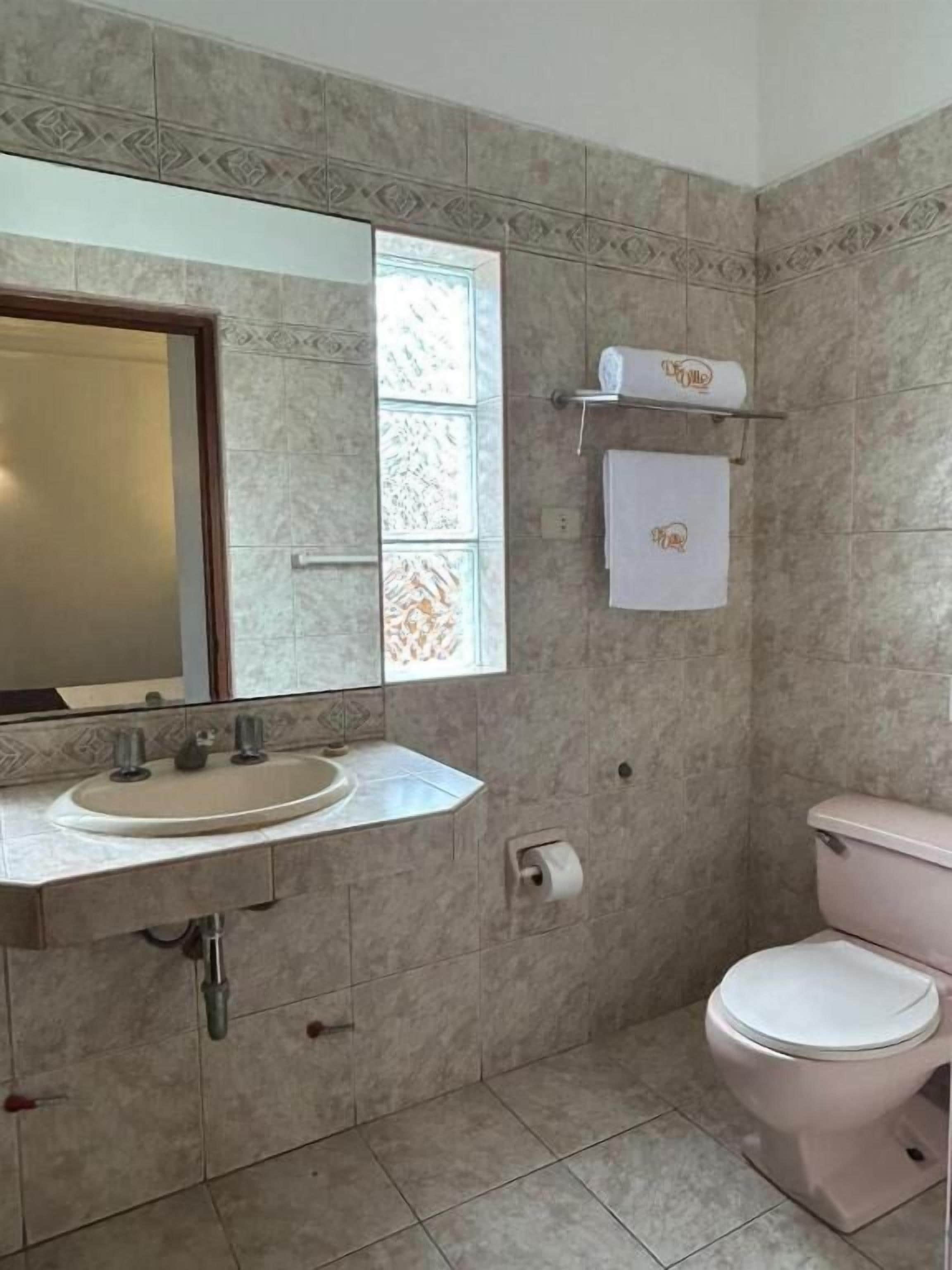 Een badkamer met een wastafel, toilet en een raam.