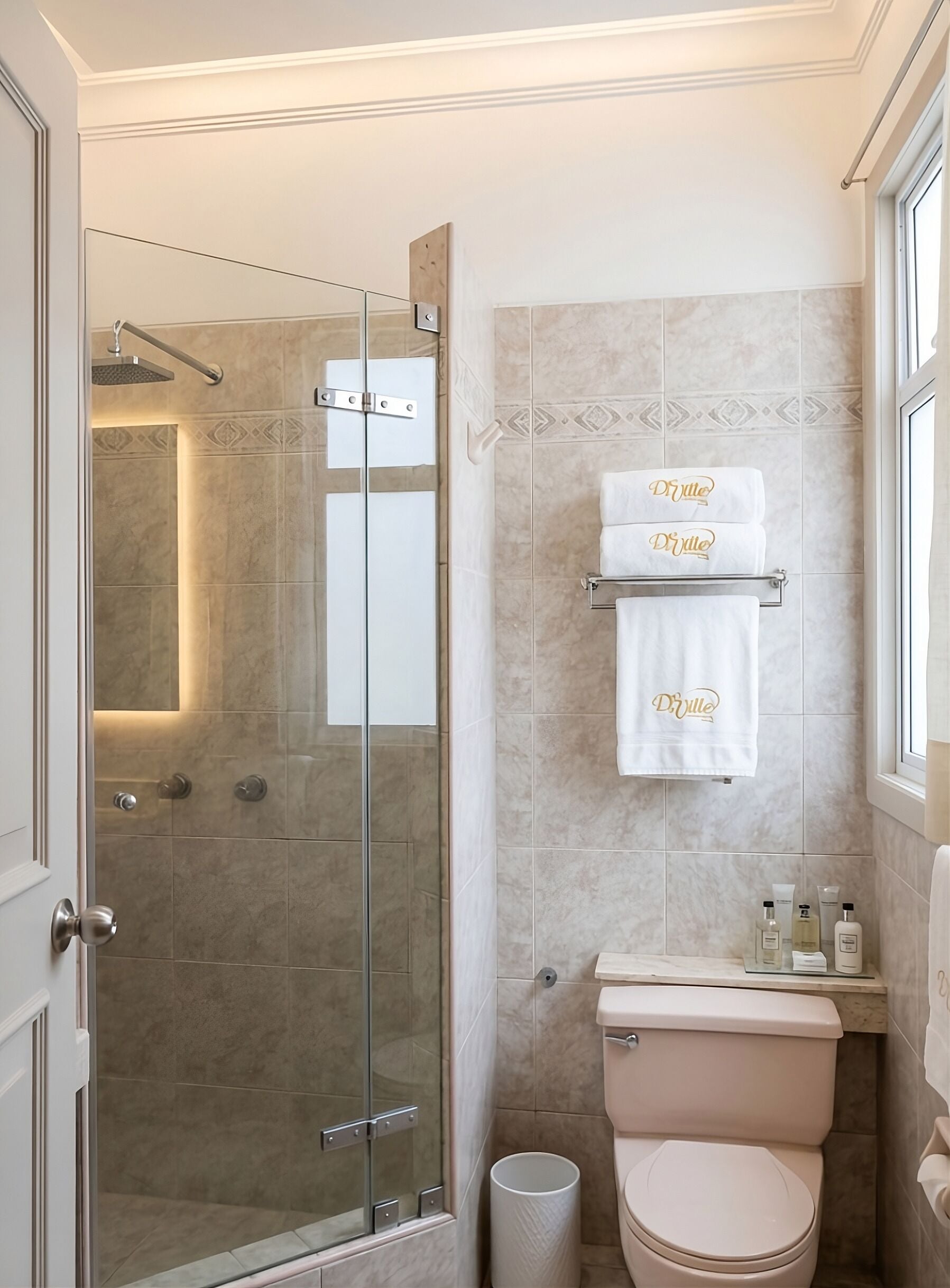 A bathroom with a glass-enclosed shower, a toilet, and a towel rack with towels.