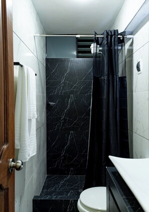 Ein Badezimmer mit Dusche, Toilette und einem Handtuchhalter mit einem weißen Handtuch.