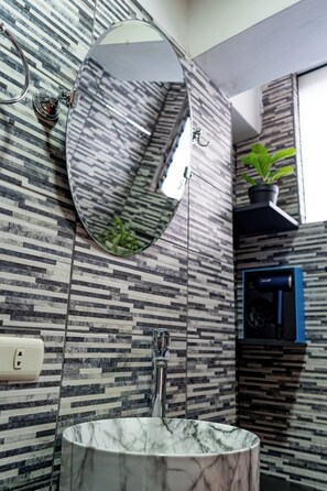 Ein Badezimmer mit Marmorwaschbecken, einem runden Spiegel und einer Wand mit Muster.