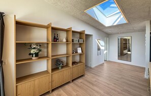 Ein Zimmer mit Oberlicht, Holzbögen und Blick durch eine Glastür.
