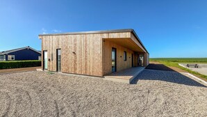 A modern wooden building with a sloped roof, a gravel driveway, and a bench in the background. - Gorgeous home in Haderslev with sauna (Haderslev)