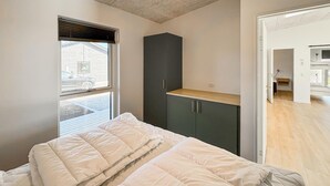 A bedroom with a bed, a window with blinds, a dark cabinet, and a wooden floor. - Gorgeous home in Haderslev with sauna (Haderslev)