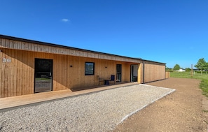 Ein modernes Gebäude mit Holzfassade, Nummer 36, mit einer Schotterauffahrt und einem Rasenfeld im Hintergrund.