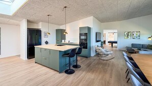 Una cocina moderna con una isla central, taburetes de bar e iluminación colgante.
