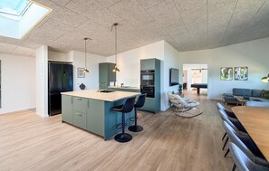 Eine moderne Küche mit Kochinsel, Barhocker und Pendelleuchten.