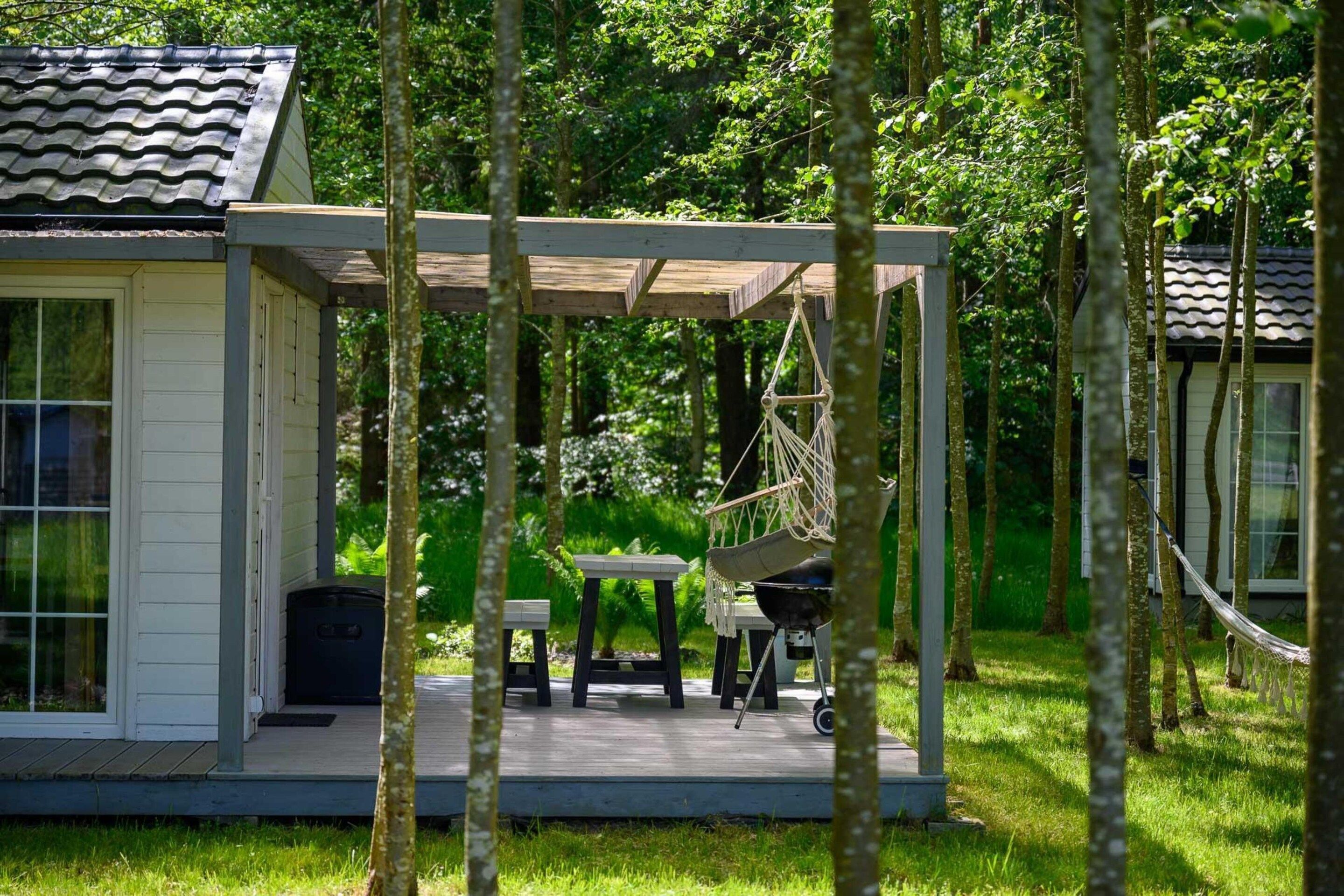 Ein kleines Haus mit Veranda, einer Hängematte und einem Grill.