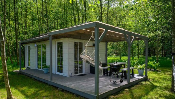 A small cabin with a porch, a hammock, and a grill area. - Comfortable Holiday Home no. 1B With a Fireplace (Darlowo)