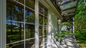 A covered outdoor area with large glass windows, a hammock, and potted plants. - Comfortable Holiday Home no. 1B With a Fireplace (Darlowo)