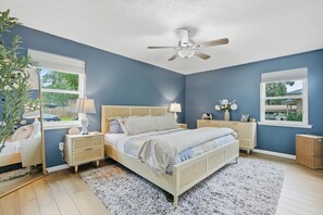 Ein Schlafzimmer mit Bett, Nachttischen, Deckenventilator und Fenster.