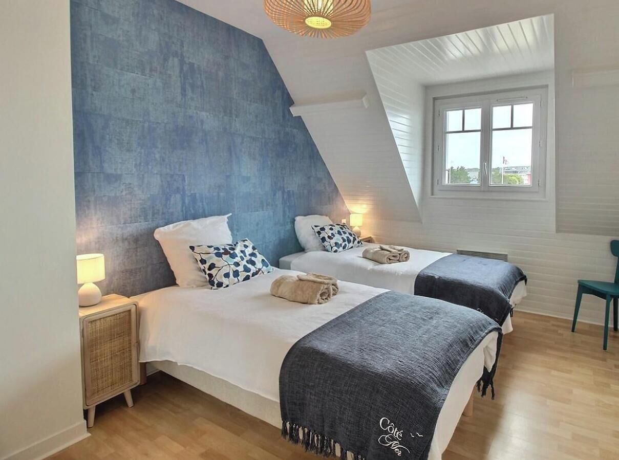Ein Schlafzimmer mit zwei Betten, einem großen Fenster, einem Deckenventilator und Blick ins Freie.