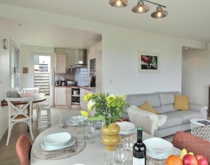 Ein modernes Wohnzimmer mit Essbereich, Küche und einer Couch mit Kissen.
