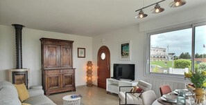 Ein Wohnzimmer mit Kamin, Fernseher, Essbereich mit gedecktem Tisch und einem großen Fenster mit Aussicht.