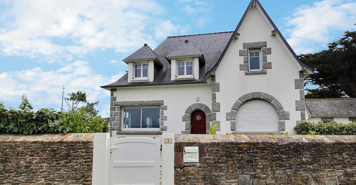 A two-story house with a stone facade, a red door, and a garage door.