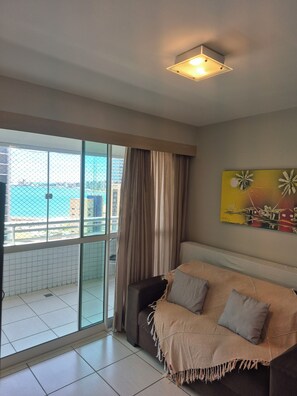 Ein Balkon mit Meerblick, eine Couch mit Kissen und ein Bild an der Wand.