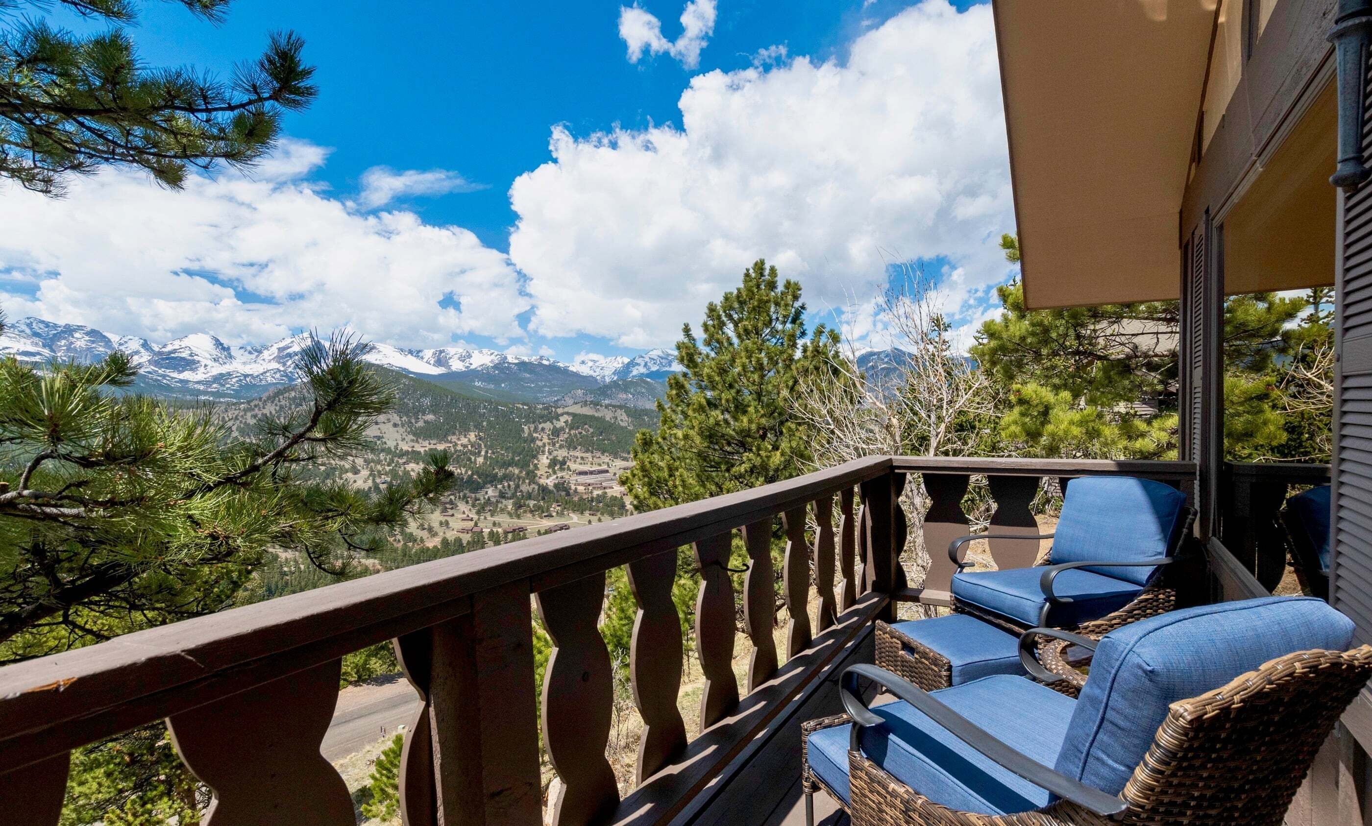A balcony with wicker chairs and a view of snow-capped mountains.