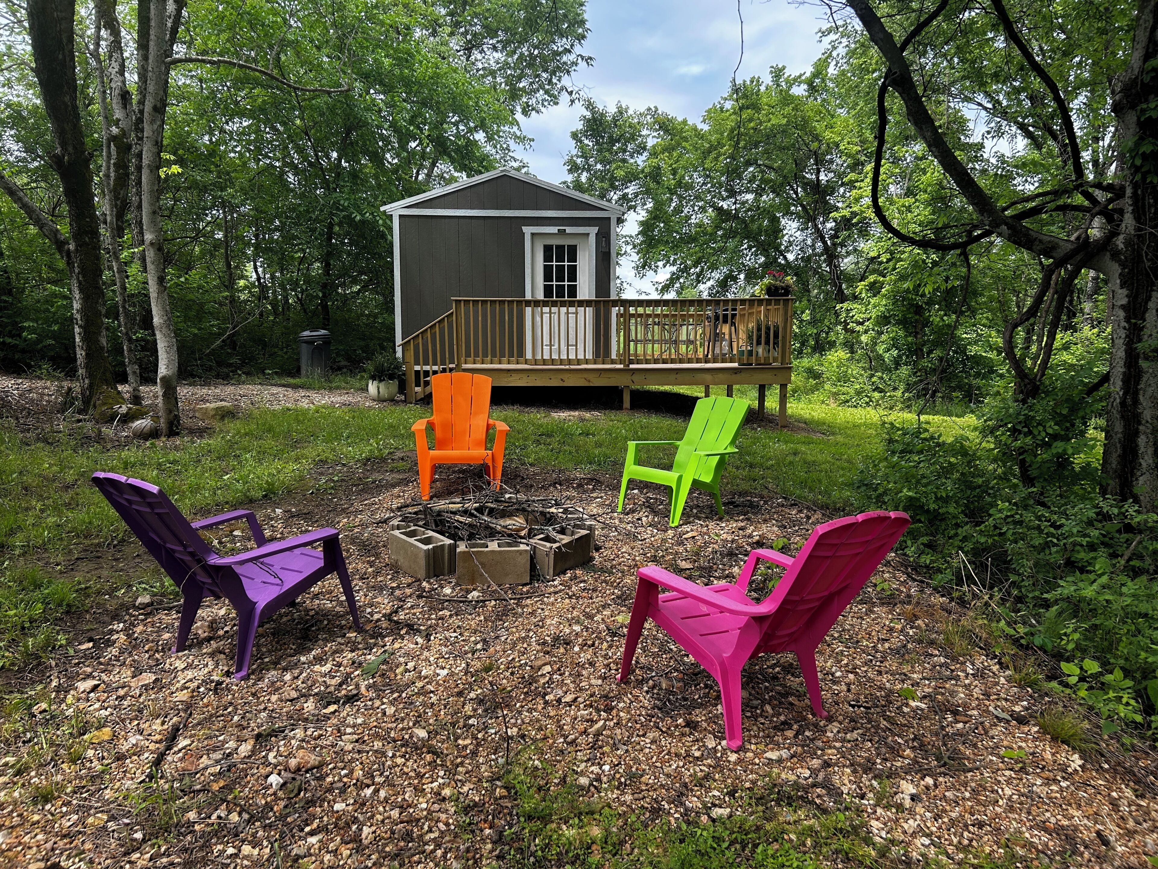 Eine Terrasse mit einem Feuerkorb und vier Adirondack-Stühlen in verschiedenen Farben.