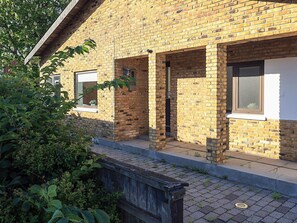 Ein Gebäude aus Ziegelsteinen mit überdachter Veranda, einer Tür und einem Fenster.