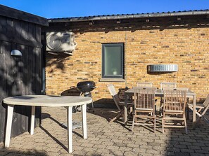Eine Terrasse im Freien mit Tisch, Stühlen, einem Grill und einer Ziegelwand.