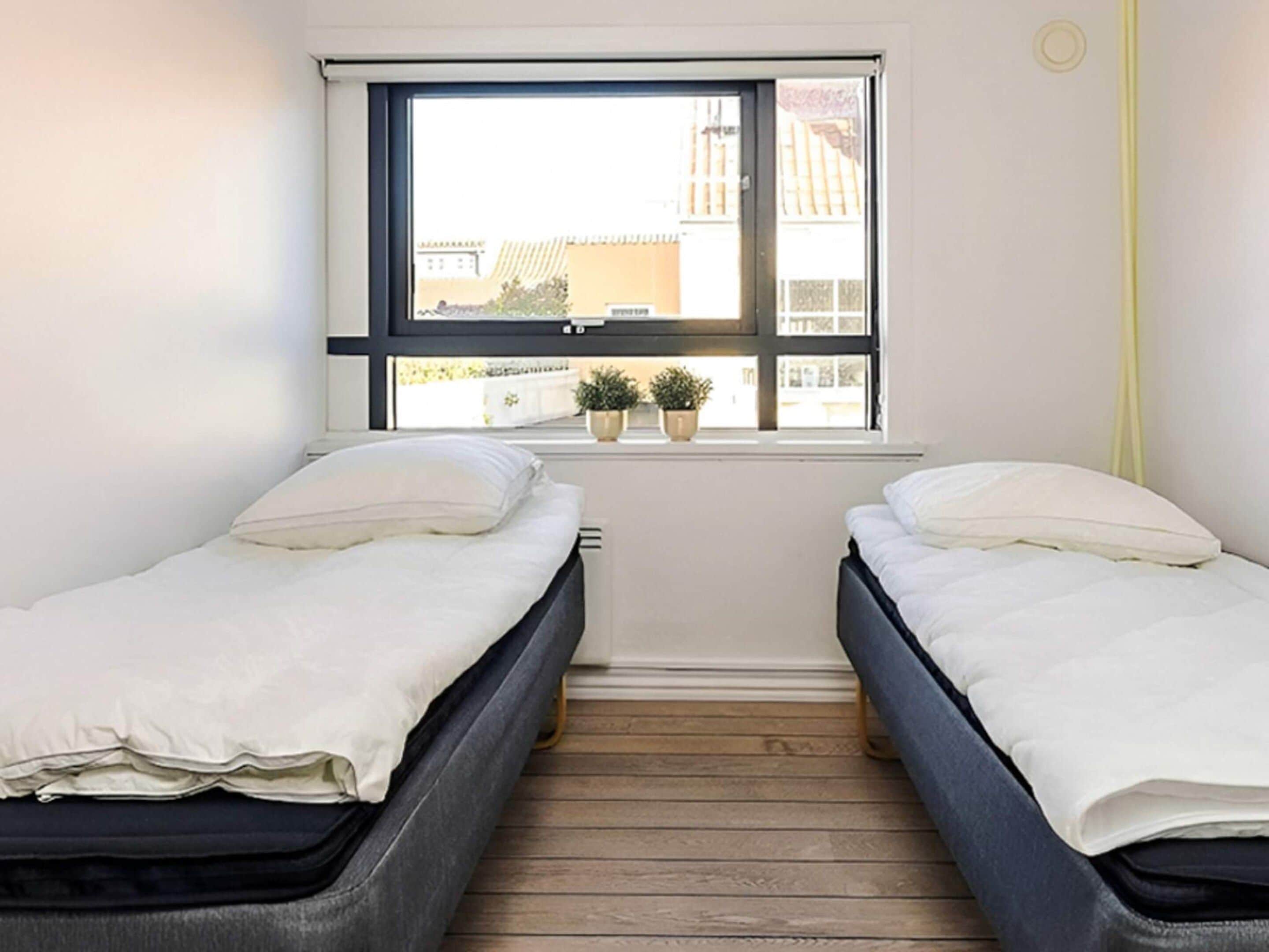 Una habitación con dos camas, una ventana y vistas a edificios.