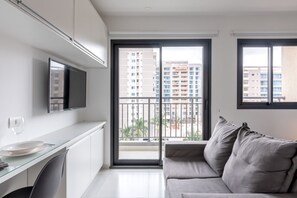 Eine moderne Wohnung mit Balkon, Flachbildfernseher, Essbereich und grauem Sofa.