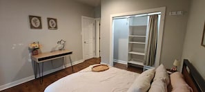 A bedroom with a bed, a desk, a chair, a wardrobe, and a mirror.