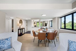 Ein modernes Wohnzimmer mit Essbereich, weißen Sofas und einem großen Fenster mit Blick.
