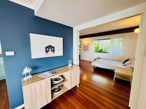 A room with a bed, a desk, a wall-mounted picture, and a window with curtains.