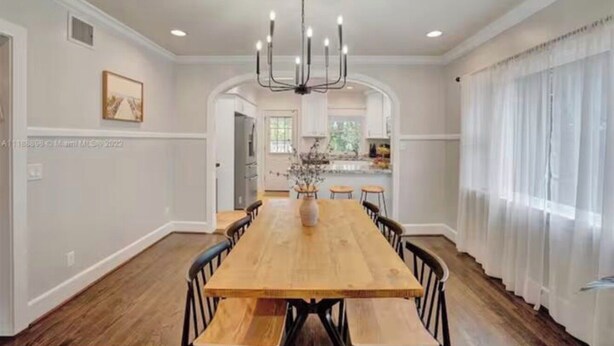A dining room with a wooden table, chairs, and a chandelier.