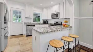 A modern kitchen with white cabinetry, a granite countertop, and a built-in island with stools.