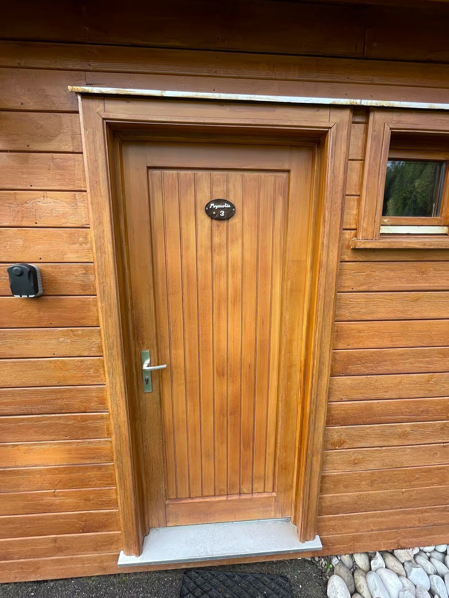 Eine Holztür mit einem Metallgriff und einem kleinen Fenster darüber.