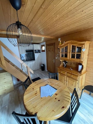 Ein Holzinterieur mit Esstisch, Stühlen, einer Küchenzeile und einer Treppe.